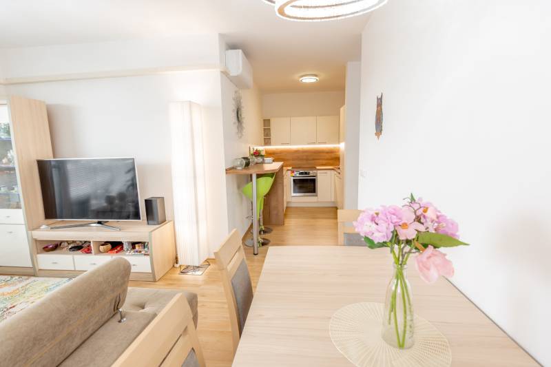 Wohnzimmer und Küche in einer 3-Zimmer-Wohnung, mit Holzmöbeln und dekorativen Blumen.