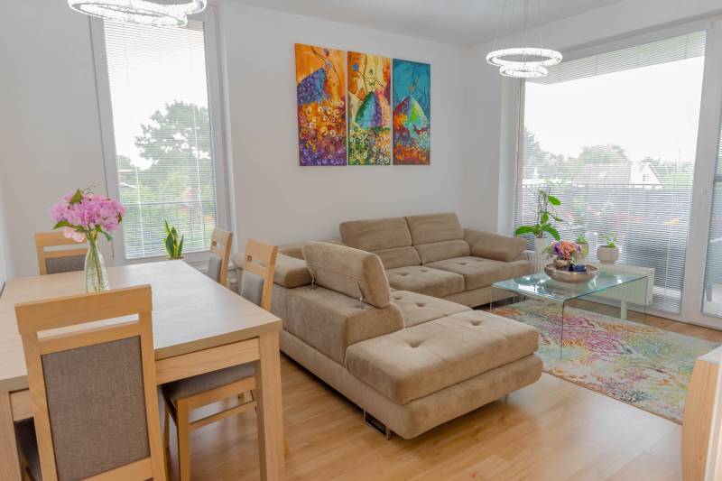 Wohnzimmer mit beigem Sofa, Esstisch und buntem Bild in einer 3-Zimmer-Wohnung.