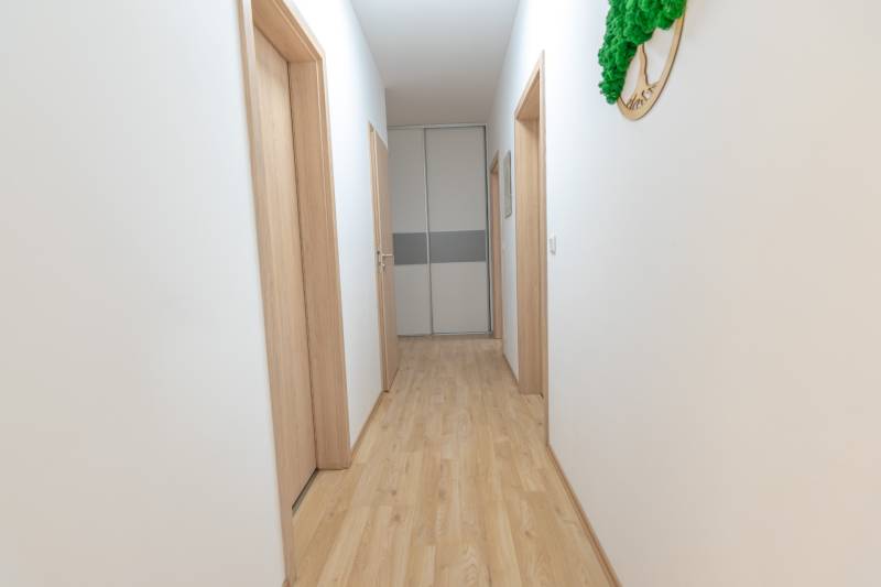 Ein heller Flur mit Holzboden und mehreren weißen Türen in einer 3-Zimmer-Wohnung.