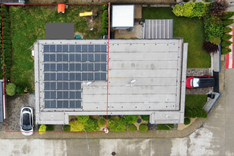 Einfamilienhaus in Povoda von oben, mit Photovoltaikanlagen auf dem Dach und einem Garten.