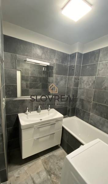Badezimmer mit grauen Fliesen und weißer Sanitäreinrichtung in einer 4-Zimmer-Wohnung.