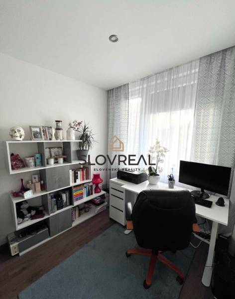 Arbeitszimmer in einer 4-Zimmer-Wohnung mit Regalen, Tisch, Stuhl und Fenster mit Vorhängen.