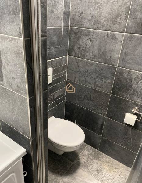 Badezimmer in einer 4-Zimmer-Wohnung mit dunkelgrauen Fliesen und Toilette.