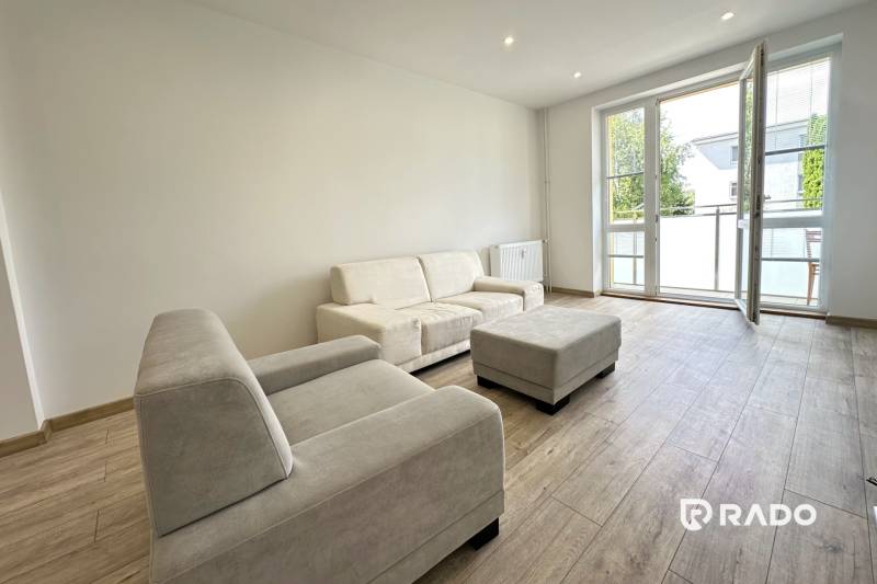 Helles Wohnzimmer in einer 2-Zimmer-Wohnung mit Sofa und großem Fenster.