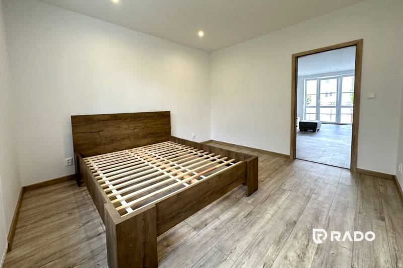 Schlafzimmer in einer 2-Zimmer-Wohnung mit Holzboden und einem Bett ohne Matratze.