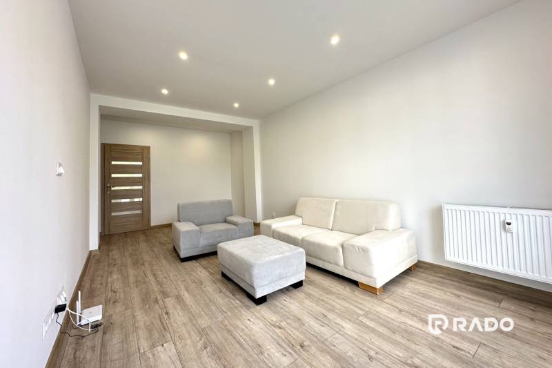 Wohnzimmer in einer 2-Zimmer-Wohnung mit Sofa, Sessel und Holzboden.