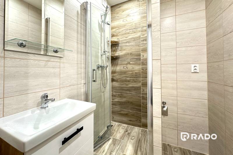 Badezimmer mit Dusche und Waschbecken in einer 2-Zimmer-Wohnung.