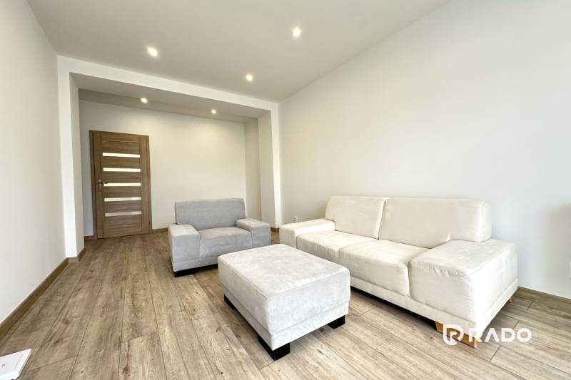 Helles Wohnzimmer in einer 2-Zimmer-Wohnung mit beigen Möbeln und Holzboden.