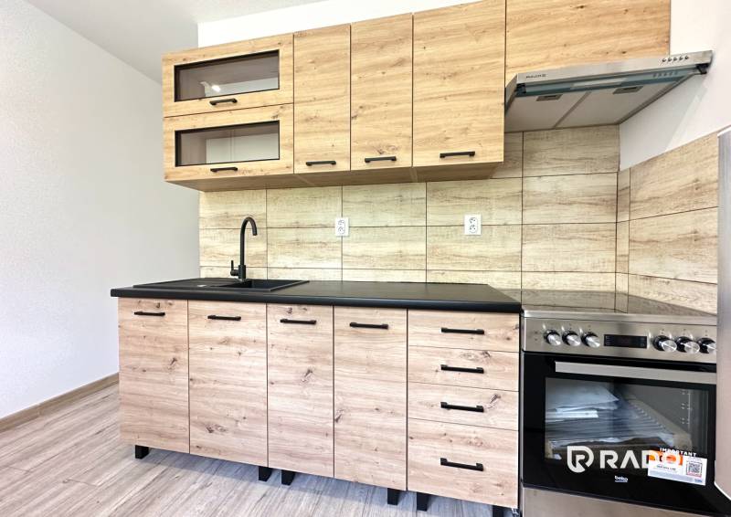 Küche mit Holzverkleidung in einer 2-Zimmer-Wohnung, ausgestattet mit Glasschränken und Herd.