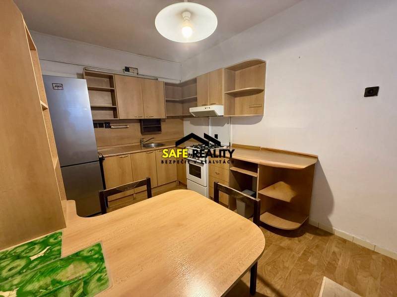 Küche in einer Einzimmerwohnung ausgestattet mit Holzmöbeln und einem Kühlschrank.