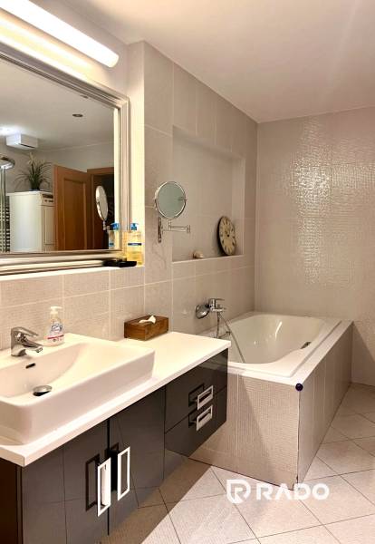 Das Badezimmer in der 3-Zimmer-Wohnung enthält eine Badewanne, ein Waschbecken und Aufbewahrungsschränke.