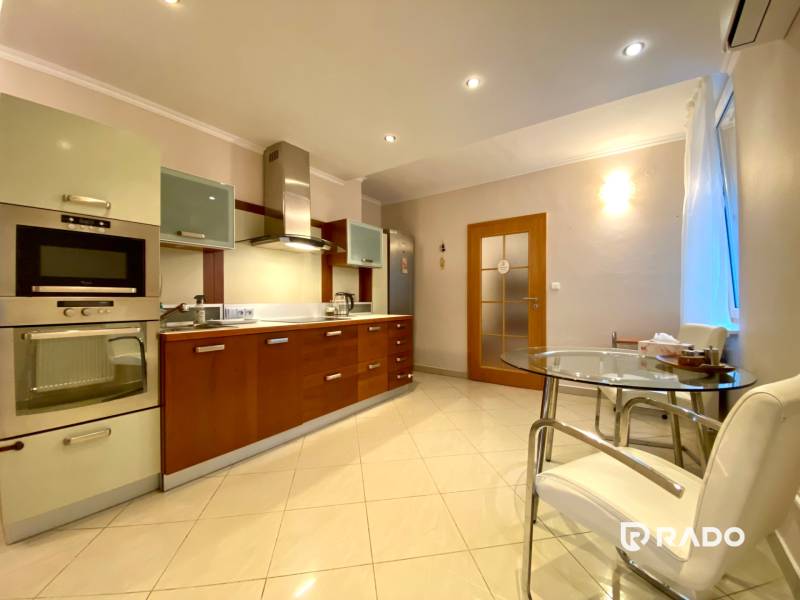 Küche in einer 3-Zimmer-Wohnung mit Edelstahlgeräten und Glastisch.