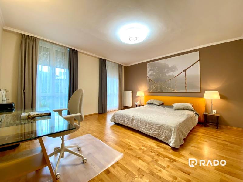 Schlafzimmer in einer 3-Zimmer-Wohnung mit einem großen Bett, einem Tisch und Parkettboden.