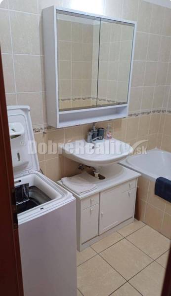 Badezimmer mit Waschbecken, Schrank, Badewanne und Waschmaschine in einer 2-Zimmer-Wohnung.