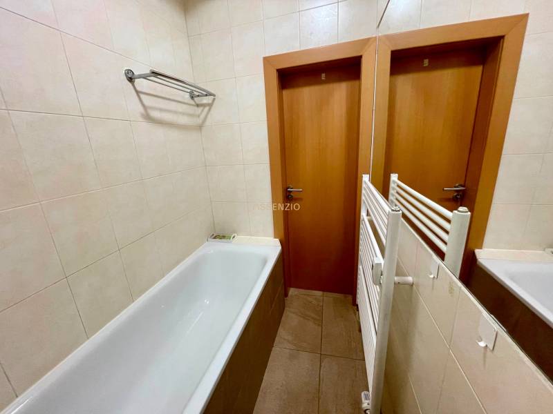 Badezimmer mit Badewanne, Fliesen und weißen Fliesen in einer 2-Zimmer-Wohnung.
