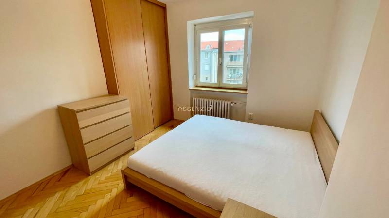 Ein Schlafzimmer mit Holzmöbeln, einem großen Bett und einem Fenster in einer 2-Zimmer-Wohnung.