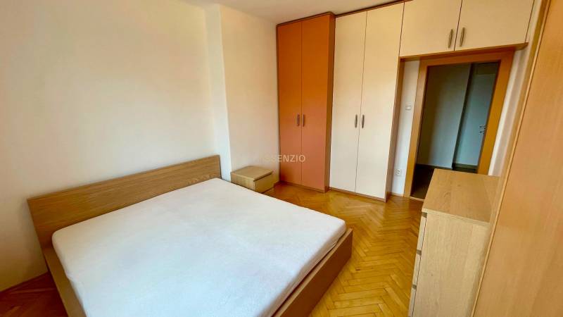 2-Zimmer-Wohnung mit Schlafzimmer, Holzboden, Bett und Einbauschränken.