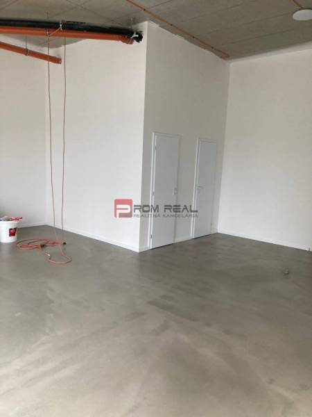 Ein leerer Raum mit Betonboden und Türen in einem Geschäftslokal.