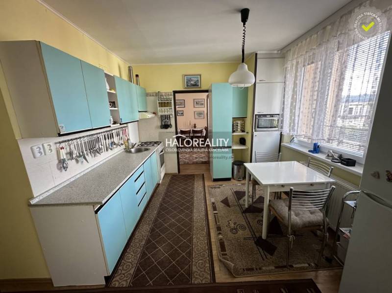 Küche in einer 3-Zimmer-Wohnung mit blauen Schränken und Esstisch.