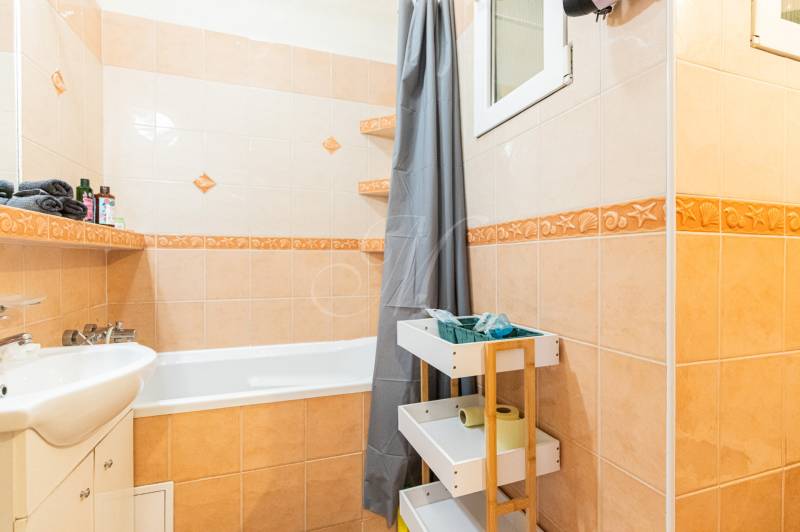 Badezimmer mit Badewanne, Waschbecken und Stauraum in einer 2-Zimmer-Wohnung.