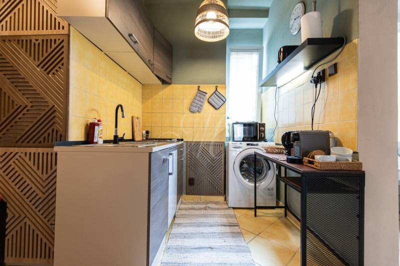Küche in einer 2-Zimmer-Wohnung mit Kochfeld, Waschmaschine und Kaffeemaschine.