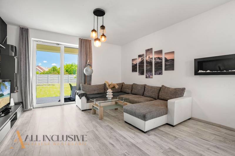 Wohnzimmer eines Einfamilienhauses mit einem bequemen Sofa und Glastüren zum Garten.