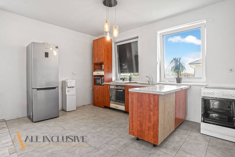 Küche mit Holzschränken, Kühlschrank und Geräten im Einfamilienhaus.