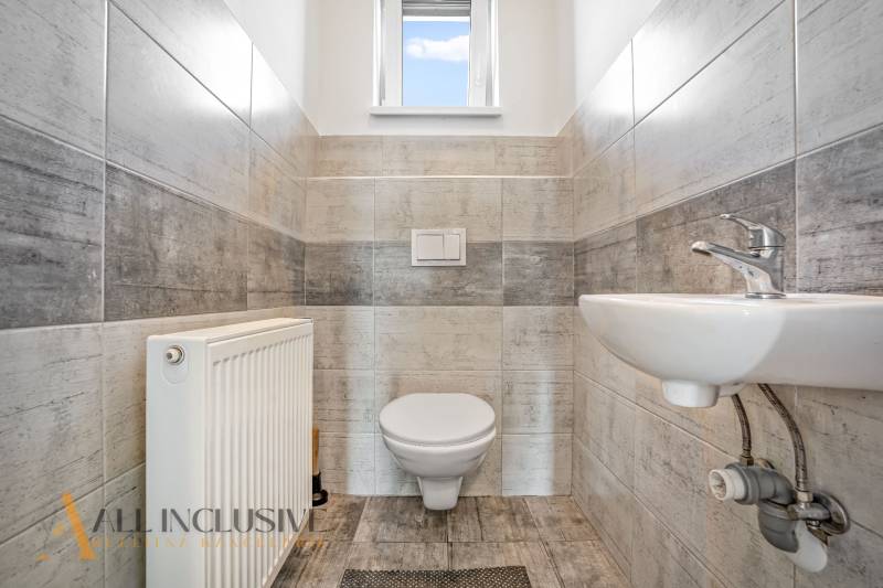Badezimmer im Einfamilienhaus mit WC, Waschbecken und Heizkörper; helle Fliesen.