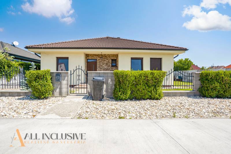 Ein Einfamilienhaus in Čečinská Potôň in Horná Potôň mit einem gepflegten Kiesgrundstück und einer Hecke.