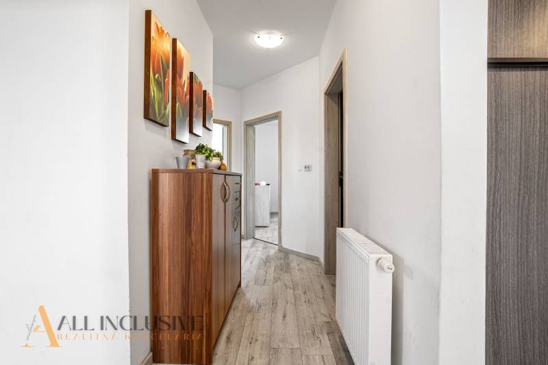Der Flur in einem Einfamilienhaus mit einer Holzkredenz und einem bunten Bild an der Wand.