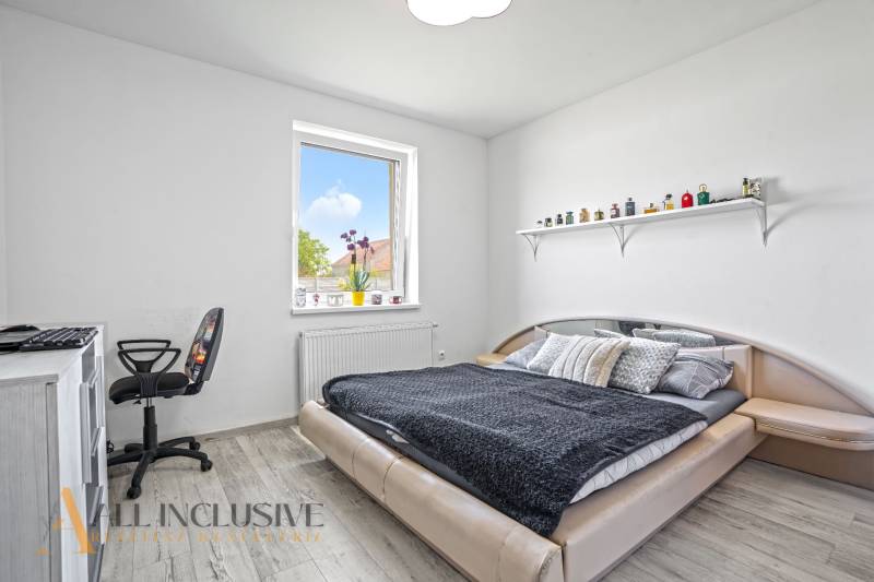 Ein Schlafzimmer in einem Einfamilienhaus mit einem Bett, einem Stuhl, einem Tisch und einem Regal an der Wand.