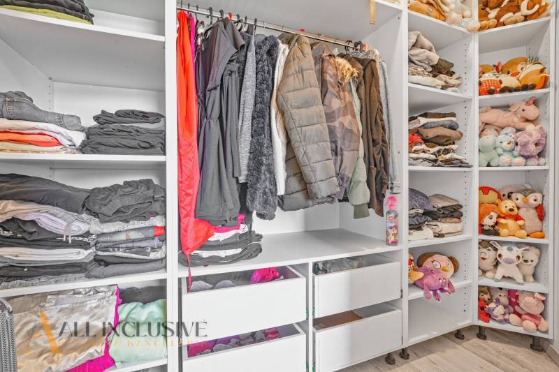 Ein Kleiderschrank im Einfamilienhaus mit Kleidung, Spielzeug und gelagerten Gegenständen in Regalen und Schränken.