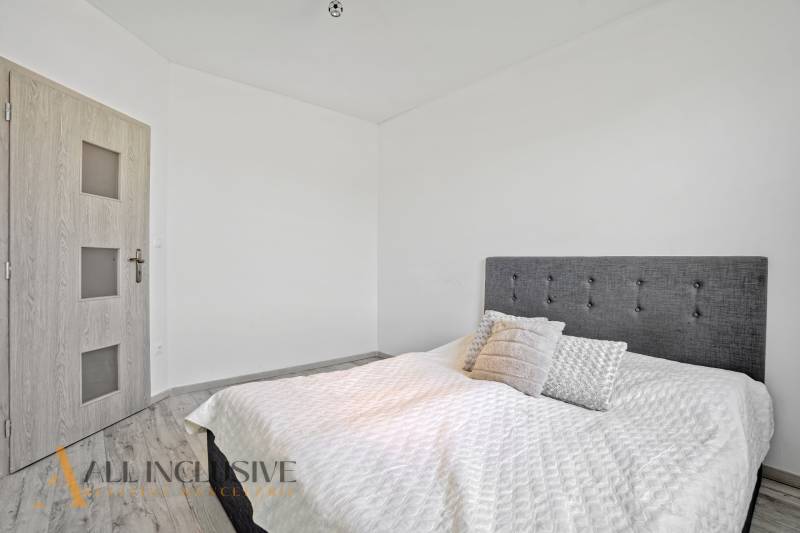 Schlafzimmer im Einfamilienhaus mit gepolstertem Kopfteil und Holztüren.