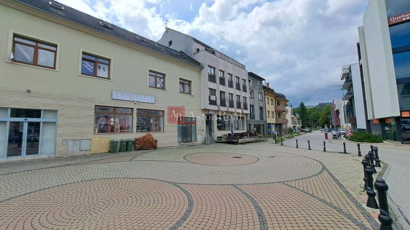 Das Gebäude in der Mostová-Straße in Ružomberok mit einem gepflasterten Platz und umliegender Infrastruktur.