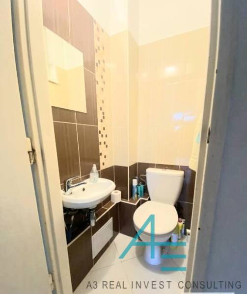 Badezimmer mit Toilette in einer 4-Zimmer-Wohnung, mit Waschbecken und dekorativen Fliesen.