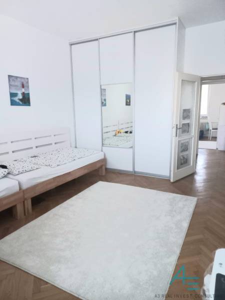 Helles Schlafzimmer mit großem Kleiderschrank und Holzbett in einer Vierzimmerwohnung.