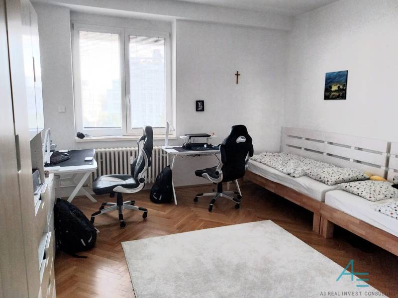 Ein Zimmer mit zwei Schreibtischen und einem Bett in einer 4-Zimmer-Wohnung.