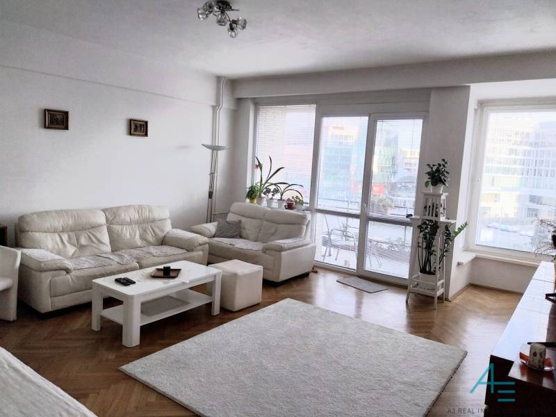Helles Wohnzimmer mit weißen Sofas in einer 4-Zimmer-Wohnung, Glastüren zur Terrasse.