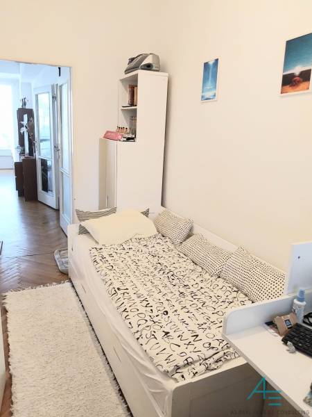 Ein Zimmer in einer 4-Zimmer-Wohnung mit einem Bett, einem Regal und einem Zugang zum Balkon.