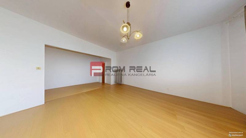 Ein geräumiges Zimmer mit Holzboden und einer Leuchte in einer 3-Zimmer-Wohnung.