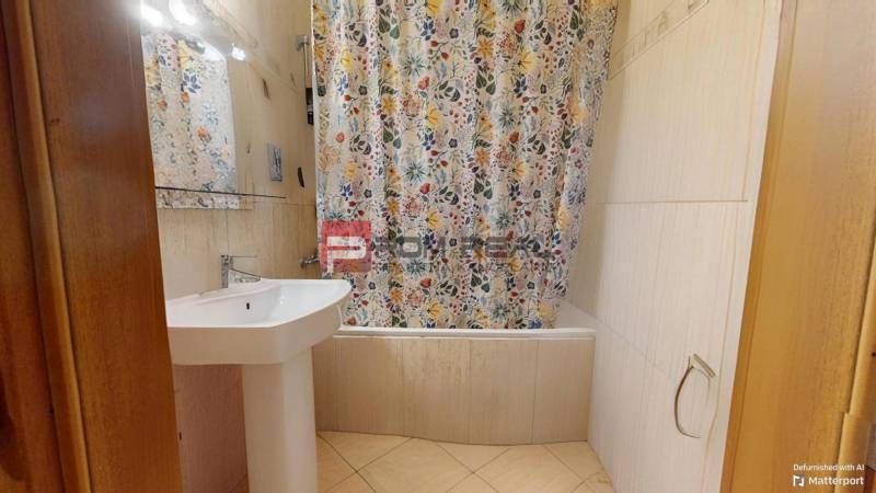Badezimmer mit Waschbecken und Badewanne mit gemustertem Duschvorhang in einer 3-Zimmer-Wohnung.