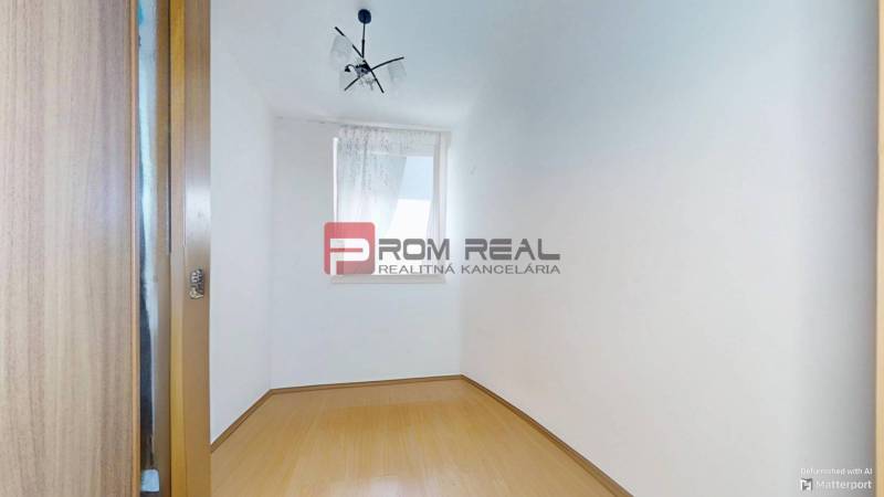 Leerer Raum mit weißen Wänden, Laminatboden und Fenster in einer 3-Zimmer-Wohnung.