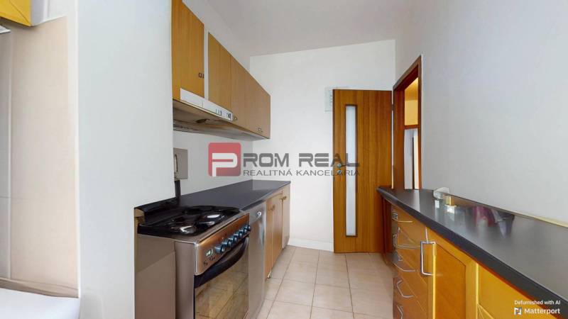 Küche in einer 3-Zimmer-Wohnung mit hellem Fliesenboden und Holzschränken.