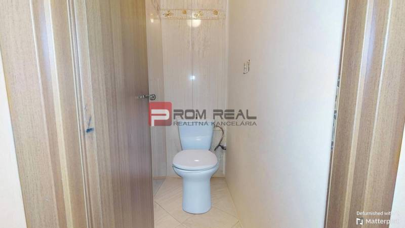 Toilette in einer 3-Zimmer-Wohnung mit hellen Fliesen und Holztüren.