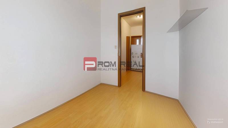 Ein Zimmer mit Holzboden und weißen Wänden in einer 3-Zimmer-Wohnung.