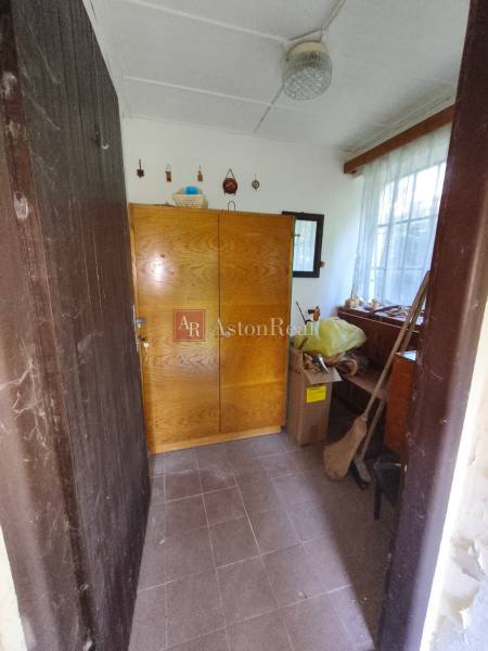 Das Innere der Hütte mit einem Holzschrank und einem Fenster, neben Pappkartons und einem Besen.