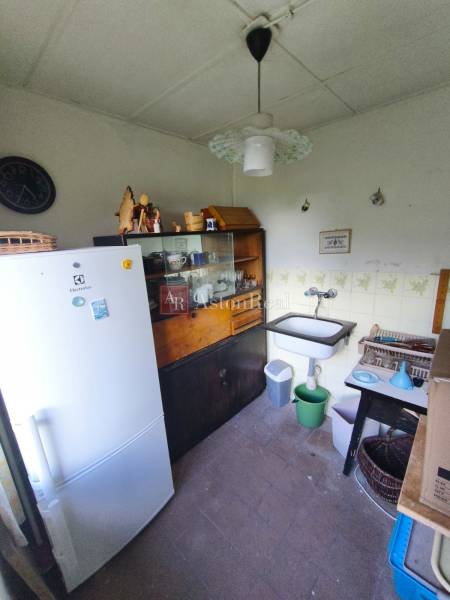 Küche in der Hütte mit Spüle, Kühlschrank, Vitrine und Uhr an der Wand.
