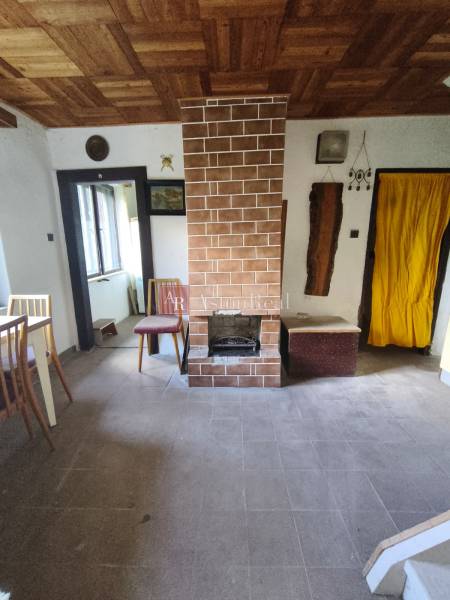 Innenraum einer Hütte mit Kamin, Fenster und Holzboden.