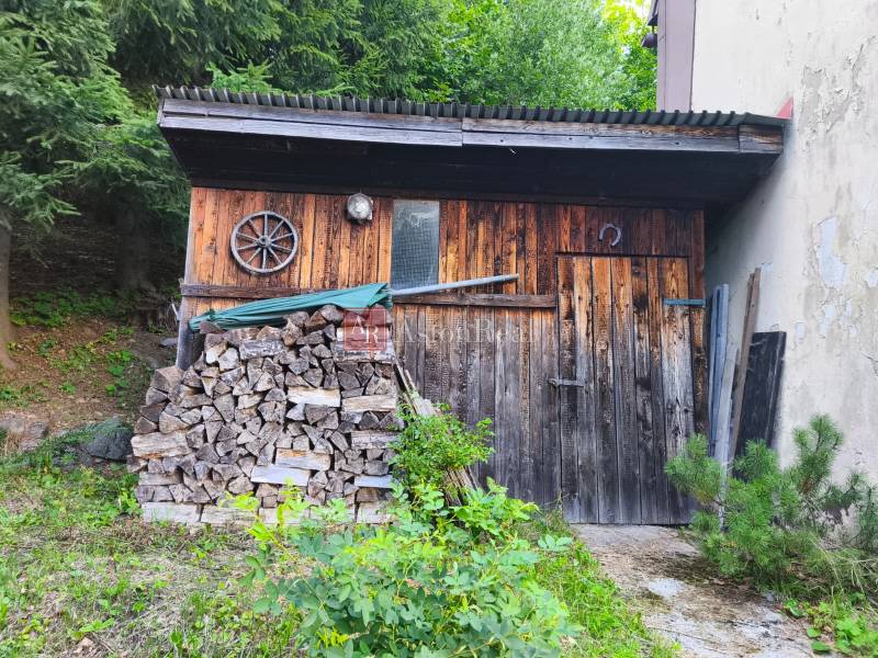 Eine Holzhütte im Wald in Kordíky bei Banská Bystrica mit gelagertem Holz.