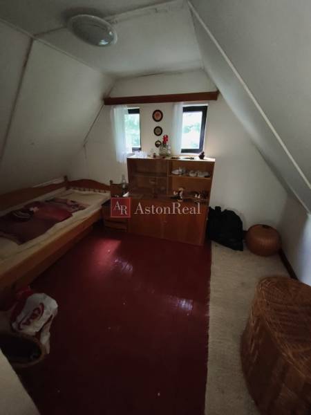 Ein Dachzimmer in einer Hütte mit einem Bett, einem Schrank und einem Boden mit Holzdekor.